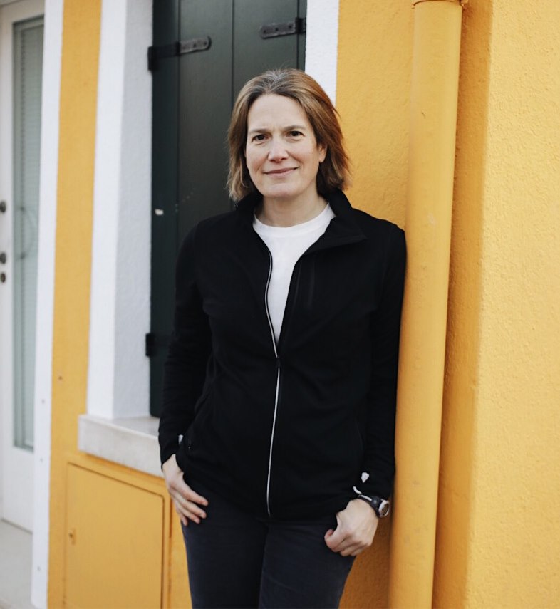 Lynne Tapper standing in front of a yellow wall